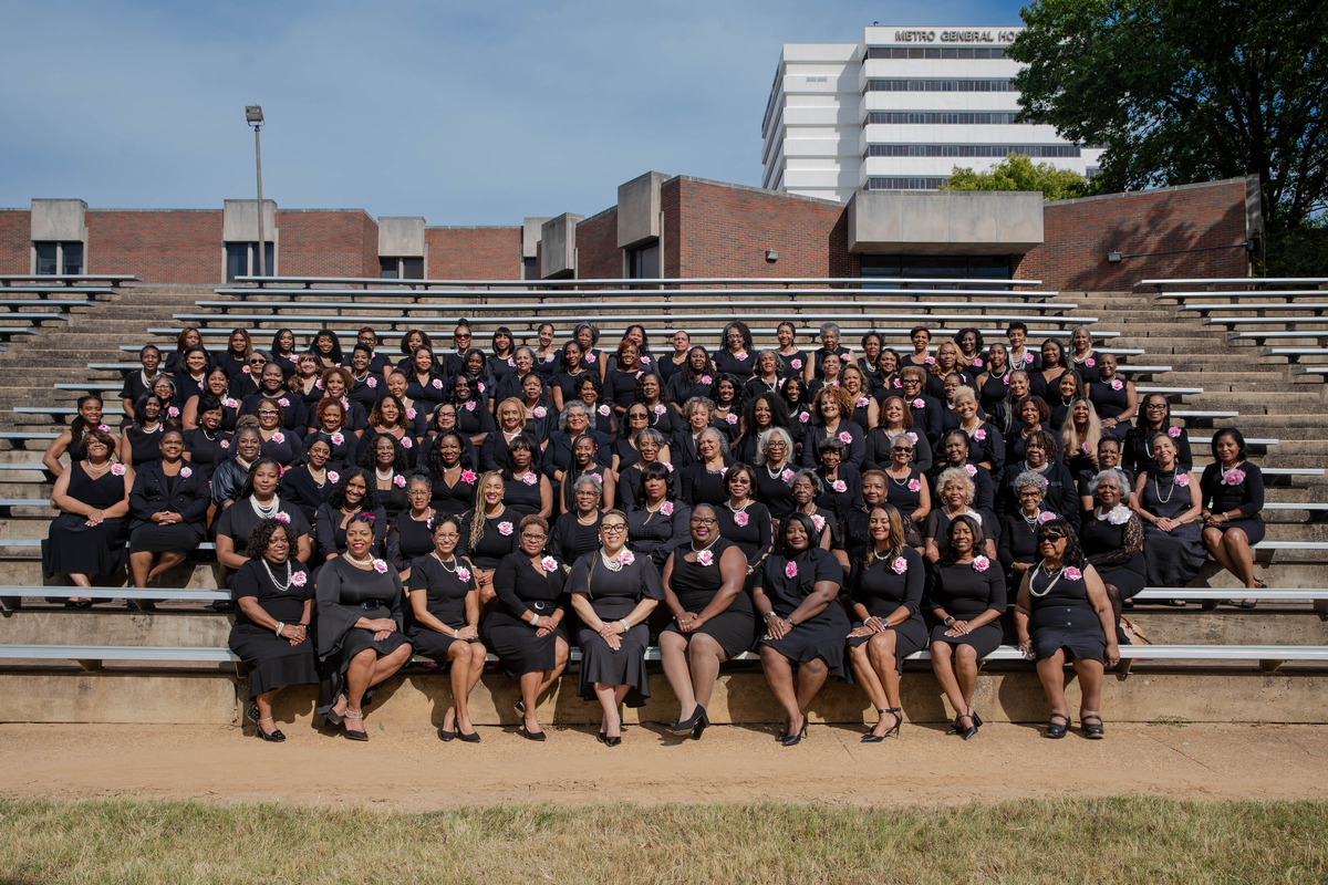 corporate group shot of a large group of African American women sitting with pink flowers on their chests taken by Nashville Corporate Media